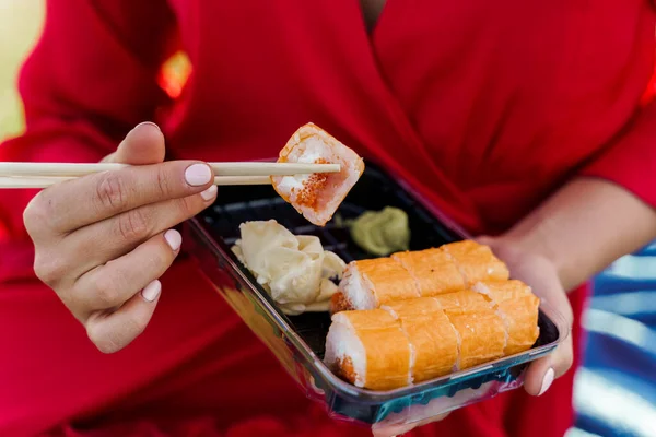 Zestaw Sushi Bliska Atrakcyjna Dziewczyna Czerwonej Sukience Trzyma Sushi Pałeczkami — Zdjęcie stockowe