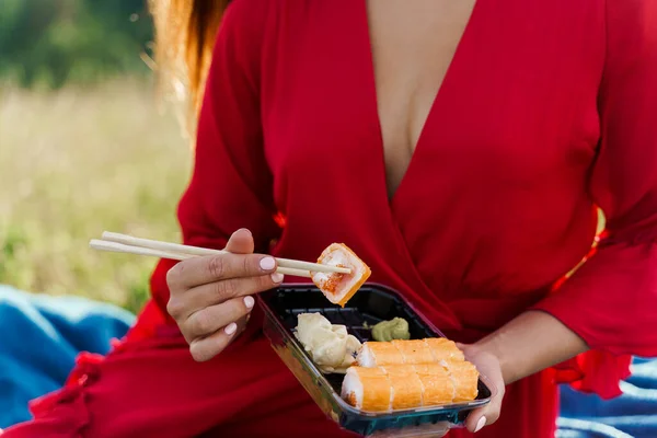 Zestaw Sushi Bliska Atrakcyjna Dziewczyna Czerwonej Sukience Trzyma Sushi Pałeczkami — Zdjęcie stockowe