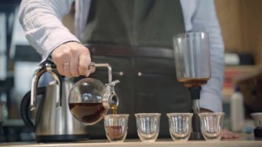Kahve ve kafede alternatif kahve senfonisi metodu. İskandinav kahvesi demleme yöntemi. Barista kahveyi dört duble bardağa doldurur.