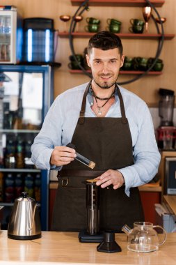 Uçak kahvesi ve kafede güzel sakallı barista. Barisa alternatif demleme metodu kullanarak lezzetli kahve pişirir. Sosyal ağlarda reklam için dikey fotoğraf.