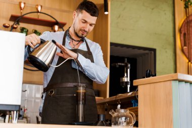 Yakışıklı barmen kafeteryada kahveyle birlikte uçağa sıcak su dolduruyor. Sakallı barista işe yarıyor. Kahveci tarafından kafede yapılan alternatif bir şey. İskandinav kahvesi demleme yöntemi.