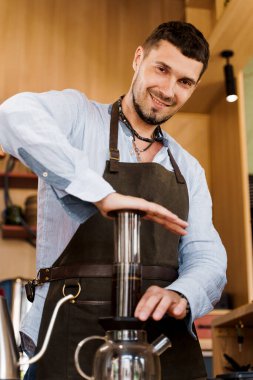 Uçak kahvesi: kahve makinesi cihaza baskı yapıyor ve kahve damlaları uçağın tepsisini demliğe döküyor. Alternatif kahve demleme yöntemi. Dikey fotoğraf yakışıklı sakallı barista lezzetli İskandinav kahvesi yapar.