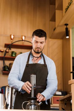 Uçak kahvesi ve kafede güzel sakallı barista. Barisa alternatif demleme metodu kullanarak lezzetli kahve pişirir. Sosyal ağlarda reklam için dikey fotoğraf.