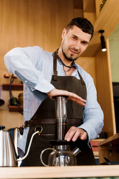 Uçak kahvesi: kahve makinesi cihaza baskı yapıyor ve kahve damlaları uçağın tepsisini demliğe döküyor. Alternatif kahve demleme yöntemi. Dikey fotoğraf yakışıklı sakallı barista lezzetli İskandinav kahvesi yapar.