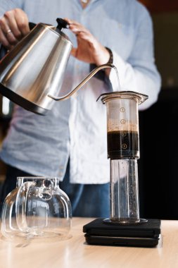 Kafe dikey fotoğrafında barista 'nın yaptığı uçak kahvesi yakın çekim alternatifi. Barista, özel bir aletle uçak kahvesi yapmak için tencereye sıcak su koyuyor. Kafeye, restoranlara yönlendir.