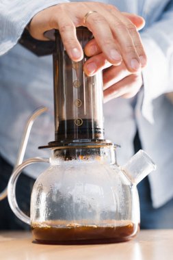 Uçak kahvesi: kahve makinesi cihaza baskı yapıyor ve kahve damlaları uçağın tepsisini demliğe döküyor. Alternatif kahve demleme yöntemi. Dikey fotoğraf yakışıklı sakallı barista lezzetli İskandinav kahvesi yapar.