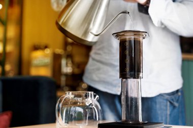 Kafede kahve yapan baristanın yaptığı uçak kahvesine yakın çekim. İskandinav kahvesi demleme yöntemi. Barista Kattle 'ı kullanarak uçağa kahve dolduruyor. Kafeye, restoranlara yönlendir.