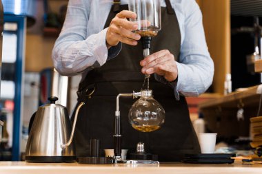 Kahve yapmak için alternatif senfoni metodu. Barista 'nın elinde kafede demlenen kahve için bir cihaz var. İskandinav kahve yapma yöntemi.