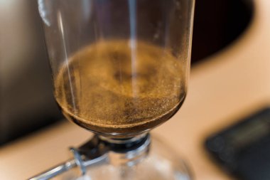 Senfoni cihazıyla demlenen kahve. Ateşle sifondaki kremalı kahveyi kapat. Ateşin üstünde demleme fotoğrafı. Alternatif kahve yapma yöntemi.