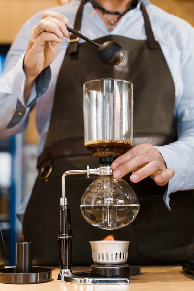 Coffee brewing by Syphon device. Close up syphon is heating by fire. Brewing photo on the fire. Alternative method of coffee making. Vertical photo for advert in social networks