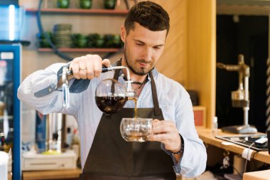 Kahve yapmak için alternatif senfoni metodu. Barista müşteriler için sifon cihazına sıcak kahve koyuyor. Kafede kahve demliyorum. İskandinav kahve yapma yöntemi.