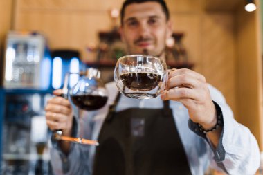 Kahve yapmak için alternatif senfoni metodu. Barista müşterilere çift cam bardakta sıcak kahve verir. Kafede kahve demliyorum. İskandinav kahve yapma yöntemi.