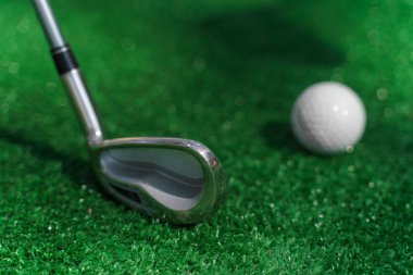 Yeşil çimlerin üzerinde golf oynamak için yakın plan Niblick ve beyaz top. Golf sopası reklamı için sağ taraf boş. Golfte oynamak