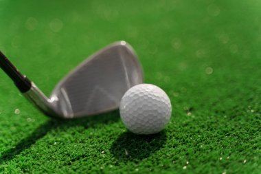 Yeşil çimlerin üzerinde golf oynamak için yakın plan Niblick ve beyaz top. Golf sopası reklamı için sağ taraf boş. Golfte oynamak