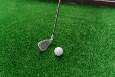 Niblick 'i kullanarak yeşil çimlerde mini golf oynamak. Oyuncu beyaz topa vuruyor. Golf sporu. Golf kulübüne yönlendir