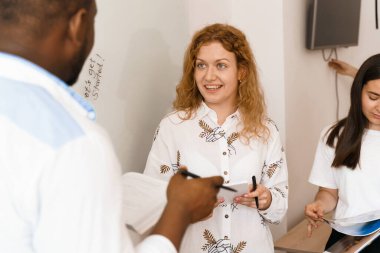 Parlak arka planda gülümseyen güzel bir öğrencinin yakın plan portresi. Mutlu kızıl kadın öğretmen meslektaşlarına gülümsüyor.