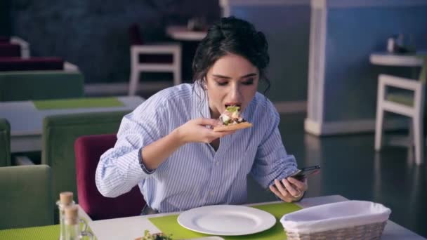 Rozmowna kobieta je pizzę i rozmawia z przyjaciółmi przez telefon w restauracji. Oddalenie się od społeczeństwa. Kobieta je pizzę w kawiarni. Ogłoszenie o pizzerii — Wideo stockowe