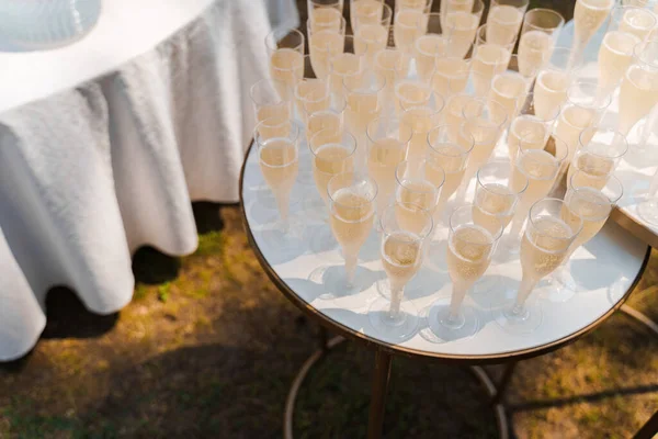 Many wine glasses on the white table. Catering for business people and wedding ceremony. Welcome drink zone with champagne in disposable plastic wine cups.
