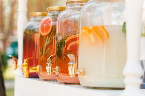 Lemonade dispenser with fruits: grapefruit, orange, lemon. Welcome zone of drinks with colourful lemonades. Non-alcoholic healthy drinks