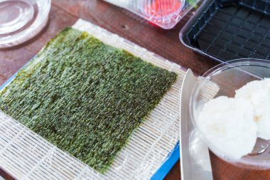 Suşi rulo tarifi, nori, pilav, somon, salatalık ve peynirli. Lezzetli Japon yemekleri. Masadaki suşi için gerekli malzemeler.