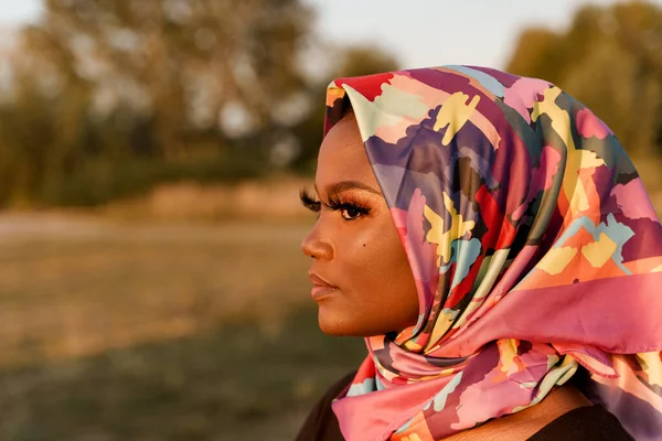 Close up african black woman weared in scarf named hijab looking left side. Traditional african clothes. Portrain of muslim woman with closed eyes. African nationality.