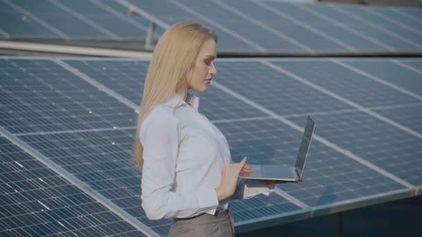 Solarmodule und Investor mit Laptop. Geschäftsfrau mit Laptop in der Nähe von Solarzellen. Ökologische Energie für Haus und Betrieb — Stockvideo