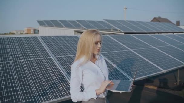Солнечные панели и инвестор с ноутбуком. Деловая женщина с ноутбуком рядом с солнечными батареями. Экологическая энергия для дома и бизнеса — стоковое видео