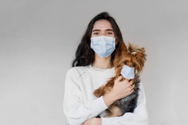 Tıbbi maskeli köpekli bir veteriner. Yorkshire Terrier 'ı çekici veteriner tutuyor. Salgın. Coronavirus konsepti. Grip salgını sırasında sağlık koruması