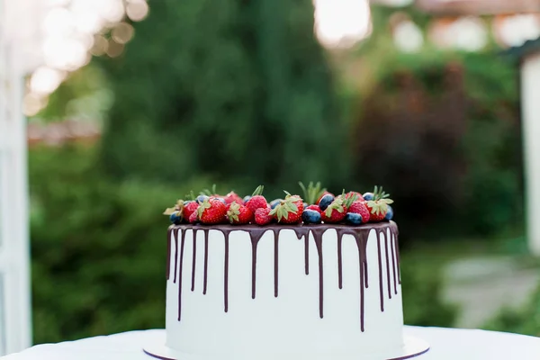 緑の背景にイチゴとブルーベリーのウェディングケーキ 儀式のための白いおいしいケーキ 料理人への広告 — ストック写真