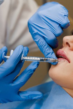 Çekici bir kız için dudak büyütme iğneleri. Estetik cerrah tıbbi klinikte dudağına iğne yapar. Kozmetik yenileme yüz tedavisi.