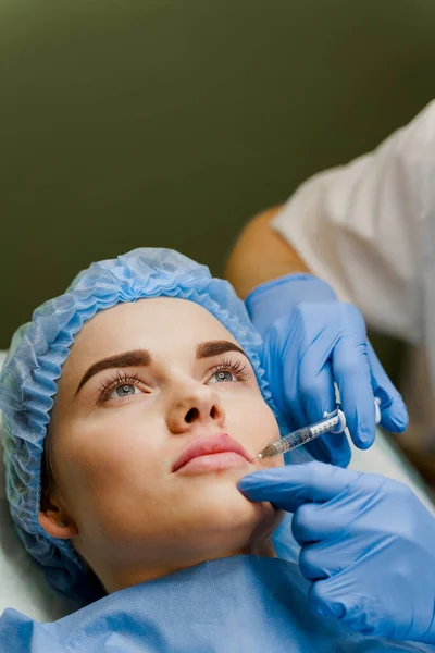 Çekici bir kız için yakın plan dudak büyütme iğneleri. Estetik cerrah tıbbi klinikte dudağına iğne yapar. Kozmetik yenileme yüz tedavisi. Reklam için boş alan