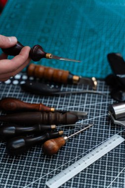 Tezgahta Leathercraft Aletleri. Geleneksel ahşap parmaklıklar ve kesiciler küçük örs çiziminin yanında zamansız işçilik ve özel tasarıma adanmışlık gösterir.