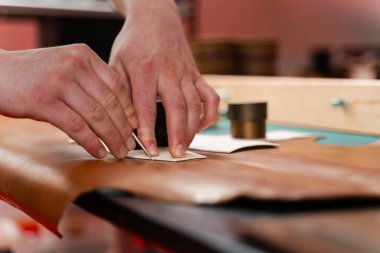 Deri işçiliği kusursuz kesim gösteriyor. Yetenekli zanaatkar deriyi doğrulukla keser. Deri kesimi desenli. Deri ustası gizlenmek için şablon kullanır