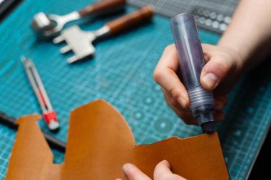 Zanaatkar koyu kenarı deri kesimine uygular, güç, pürüzsüzlük ve incelik ekler. Boyama işaretiyle bitiş çizgisinde. Esnaf deri parçasına kenar boyası sürerek dayanıklılığı arttırır.