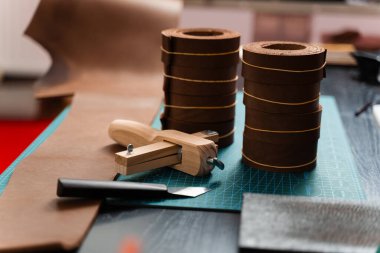 Deri rulo ve kayış kesici, güçlü kemerleri ve deri ürünleri budamak için hazır bir şekilde hasırın üzerinde yatar. Keskin kayış kesici ve deri rulo, kemer kayışları için gerekli.