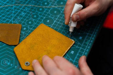 Deri kenarlara yapıştırıcı sürüyorum. Deri ürünler üretimi güçlü bir yapıştırıcıyı güvenli bir şekilde kenetleyerek başlar. Deri ustaları dikiş atmadan önce kenar hazırlamak için yapıştırıcı kullanır.