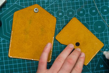 Deri kenarlara yapıştırıcı sürüyorum. Deri ürünler üretimi güçlü bir yapıştırıcıyı güvenli bir şekilde kenetleyerek başlar. Deri ustaları dikiş atmadan önce kenar hazırlamak için yapıştırıcı kullanır.