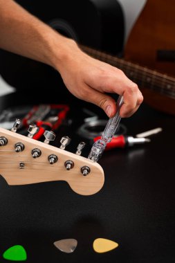 Gitar telleri cilalanmış bir başlık üzerinde temiz bir plastik Winder ile sıkılaştırılır. Gitar Bakım ve İp Değiştirme. Gitar başlığı bir iple ayarlanıyor.