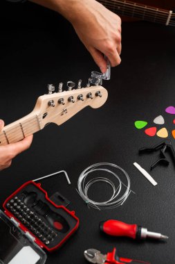 Gitar Bakım ve İp Değiştirme. Gitar başlığı bir ip cambazıyla ayarlanıyor. Gitar telleri cilalanmış bir başlık üzerinde açık plastik bir Winder ile sıkılaştırılır.