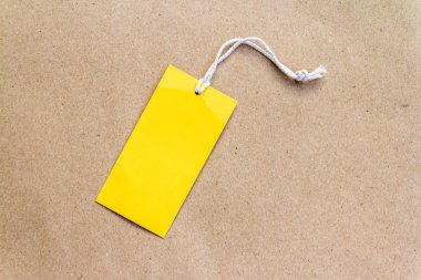 kopya alanı ile kahverengi kağıt arka planda bir boş sarı fiyat etiketi