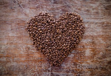üst görünüm, ahşap yüzeyde izole kalp şeklinde kavrulmuş kahve çekirdekleri 