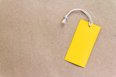 kopya alanı ile kahverengi kağıt arka planda bir boş sarı fiyat etiketi