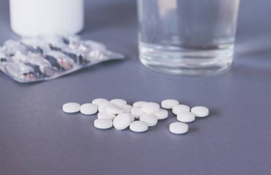 masa ve su bardağı üzerinde beyaz yuvarlak haplar 