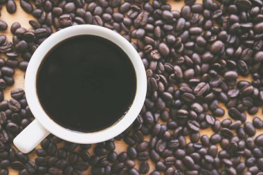 Masa yüzeyinde espresso ve kahve tohumları ile beyaz kahve bardağı 