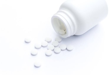 Masa yüzeyinde şişe ve beyaz haplar