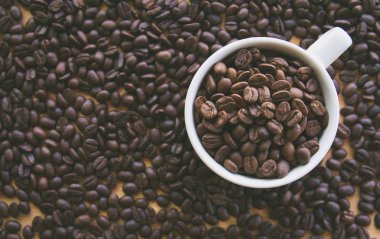 kahve çekirdekleri dolu beyaz kahve bardağı, Masa yüzeyinde tohumlar 