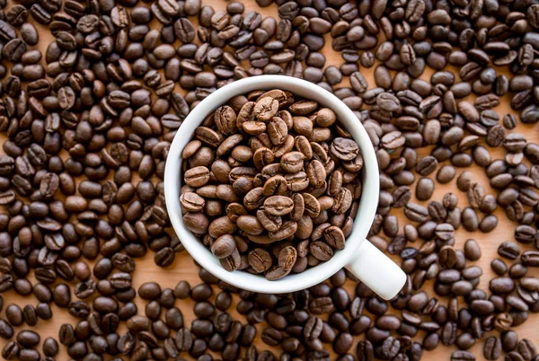 Weiße Kaffeetasse Voller Kaffeebohnen Samen Auf Der Tischfläche — Stockfoto