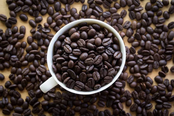 Braune Geröstete Kaffeebohnen Auf Tisch Und Weiße Tasse Draufsicht — Stockfoto