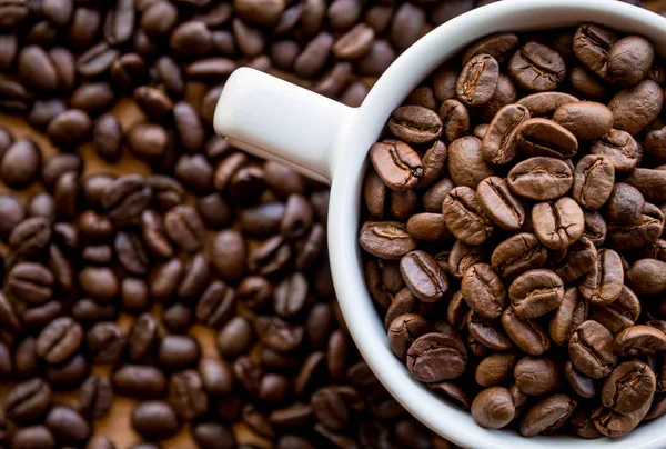 Weiße Kaffeetasse Voller Kaffeebohnen Samen Auf Der Tischfläche — Stockfoto