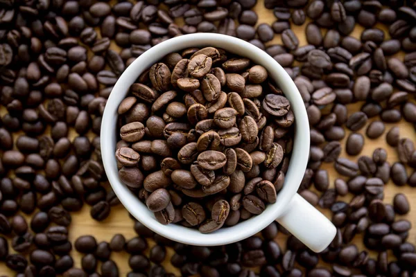 Weiße Kaffeetasse Voller Kaffeebohnen Samen Auf Der Tischfläche — Stockfoto